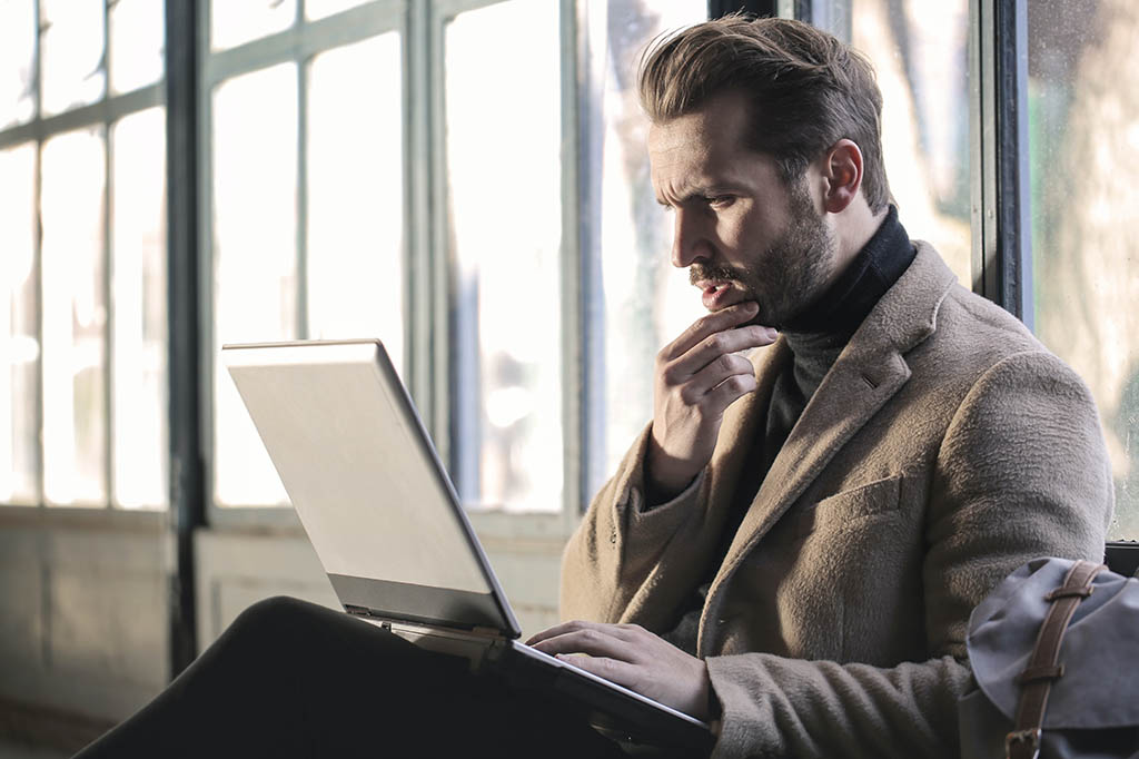 concerned looking man looking at laptop
